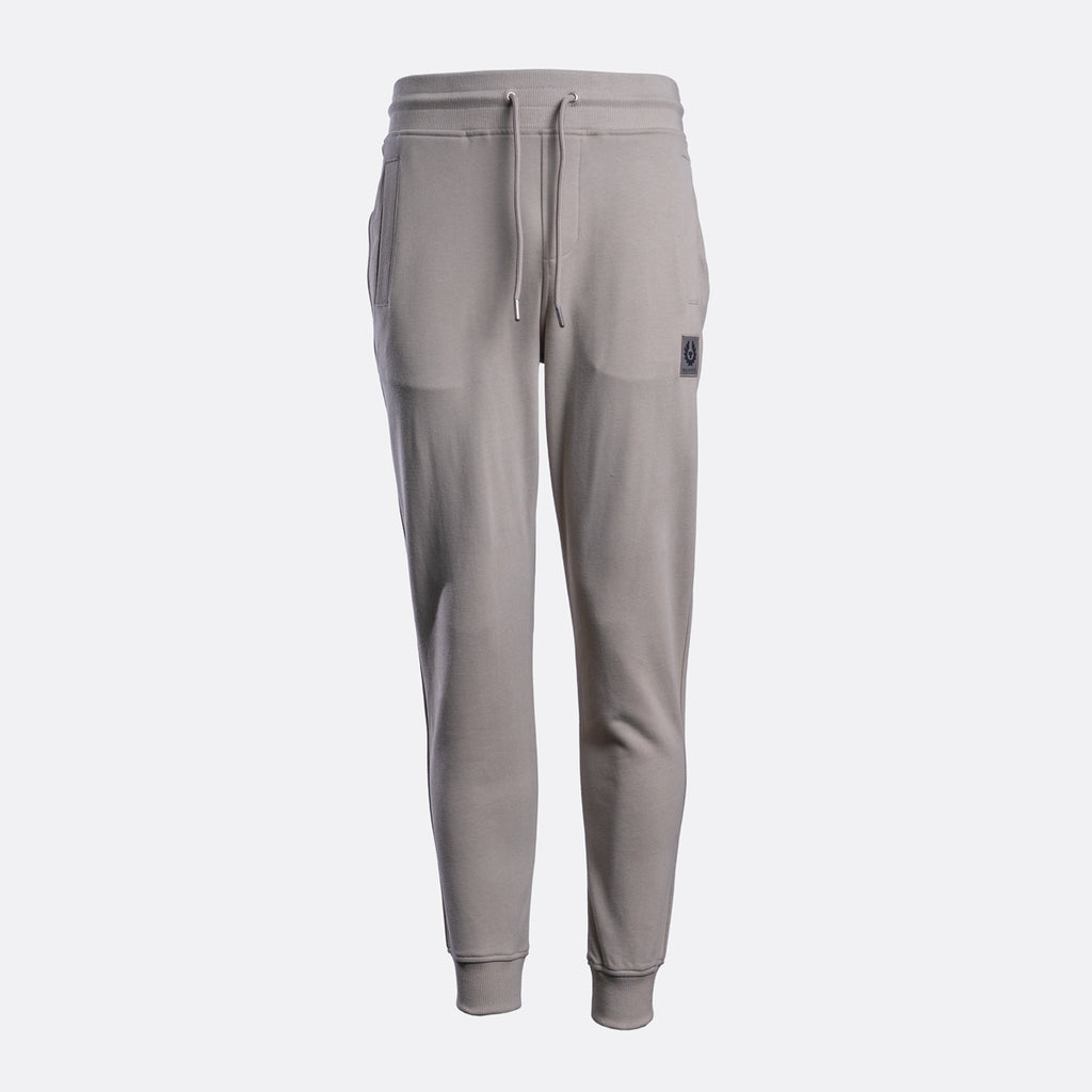A pair of light gray sweatpants with a drawstring waist, side pockets, and ribbed cuffs, shown against a light gray background. Belstaff Sweat Pants. Sakks Menswear Southampton.
