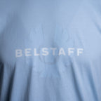 Close-up of a light blue t-shirt featuring a tonal, semi-transparent graphic of a sunburst with the word 'BELSTAFF' printed across the center. Belstaff T-Shirt. Sakks Menswear Southampton.