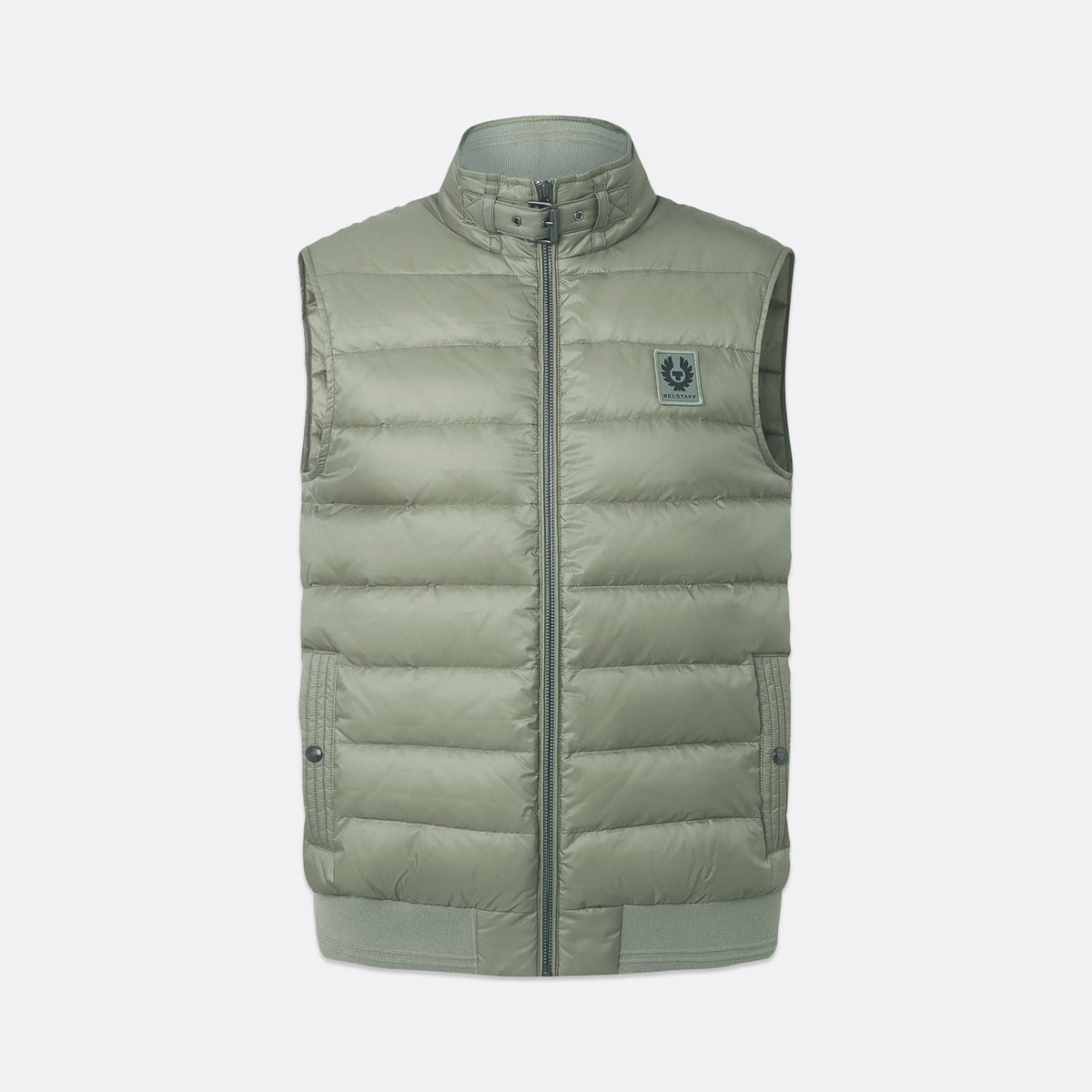 A sleeveless quilted puffer vest in a muted sage green color, featuring a stand-up collar, front zipper, and a small circular logo patch on the left chest, shown against a light gray background. Belstaff Gilet. Sakks Menswear Southampton.