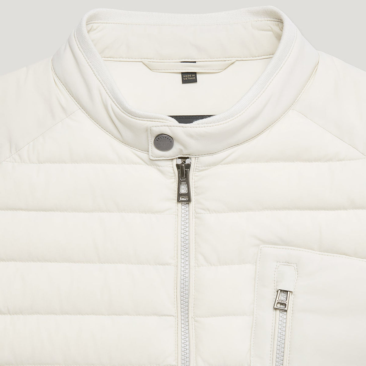 Close-up of a white puffer jacket with a stand-up collar, silver zipper, and a small visible GANT neck label. Belstaff Gilet. Sakks Menswear Southampton.