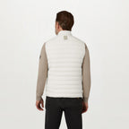A man viewed from the back wearing a white quilted puffer vest over a beige long-sleeve shirt and black pants, against a plain white studio background. Belstaff Gilet. Sakks Menswear Southampton.