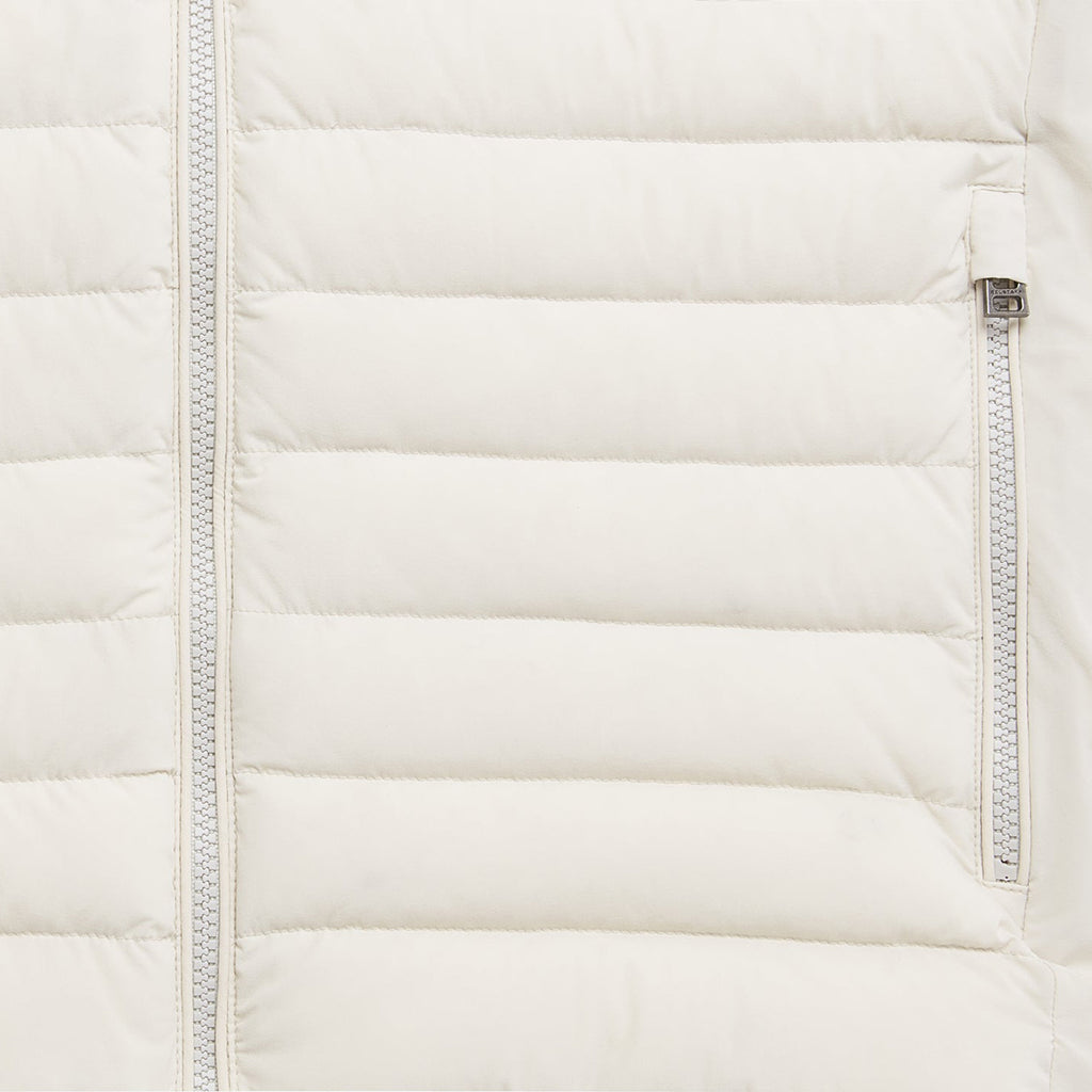 Close-up of a quilted puffer jacket in off-white, showing horizontal stitching, a front zipper, and a side zip pocket with a silver zipper pull. Belstaff Gilet. Sakks Menswear Southampton.