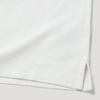Close-up of a white folded garment, showing the hem with a small side slit and fine stitching against a light neutral background. Belstaff Polo. Sakks Menswear Southampton.