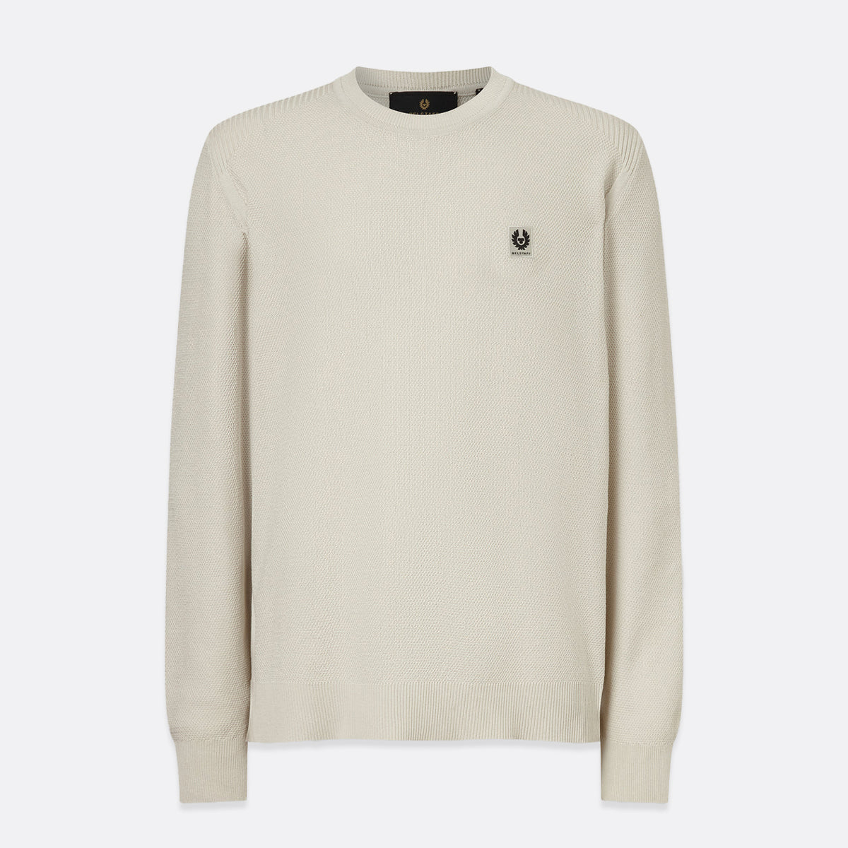 A cream-colored long-sleeve knit sweater with a small embroidered black logo on the left chest, displayed against a light gray background. Belstaff Sweatshirt. Sakks Menswear Southampton.