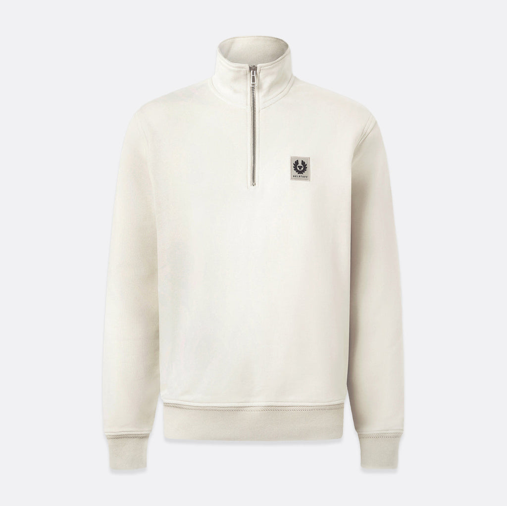 An off-white quarter-zip sweatshirt with a small embroidered logo patch on the left chest, displayed on a light gray background. Belstaff Quarter Zip. Sakks Menswear Southampton.
