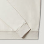 Close-up detail of a crewneck sweatshirt showing the sleeve cuff and ribbed hem in a warm off-white or cream colour. Belstaff Quarter Zip. Sakks Menswear Southampton.