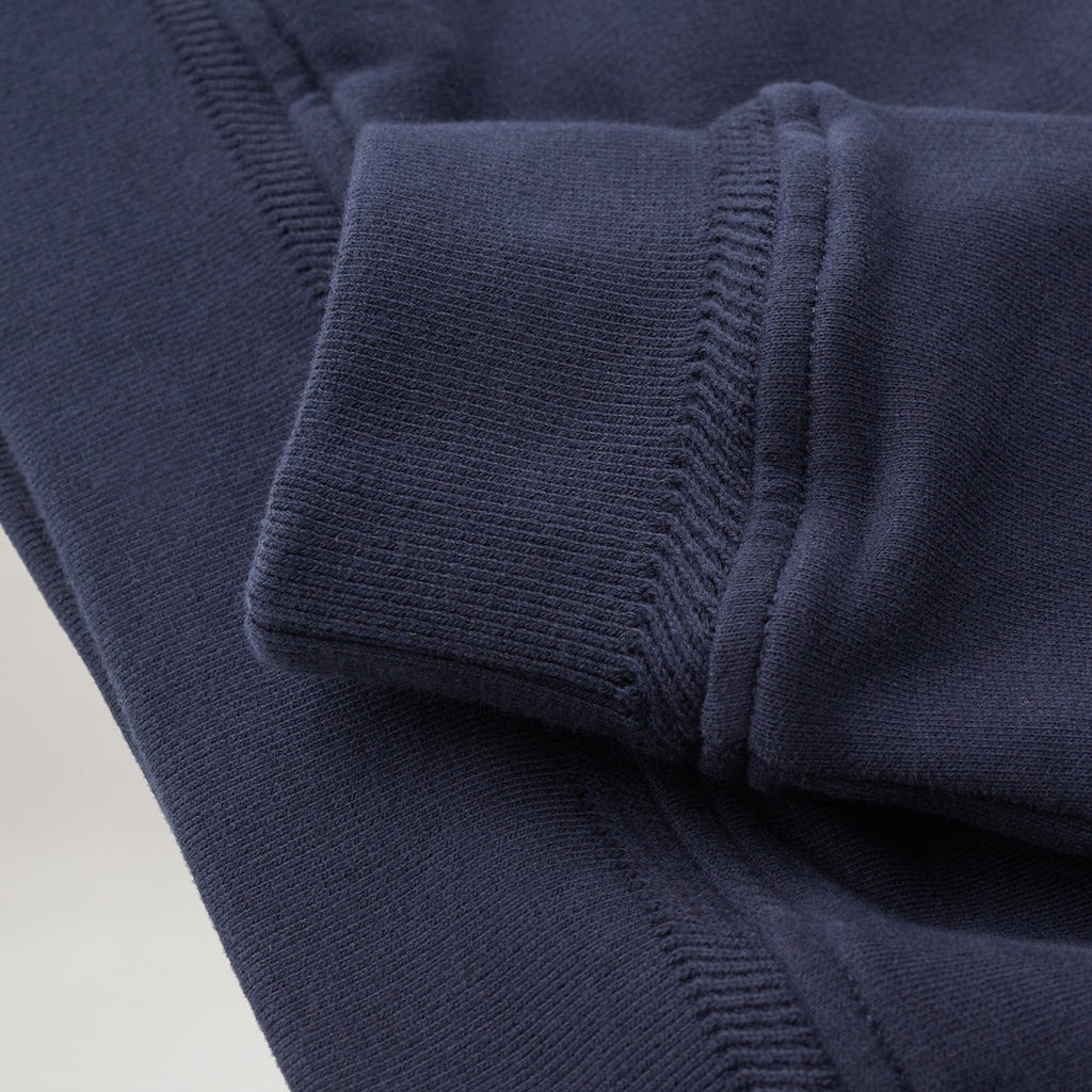 Close-up of a navy blue ribbed knit garment, showing the cuff and sleeve construction with fine fabric texture. Belstaff Quarter Zip. Sakks Menswear Southampton.