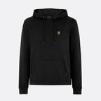 A black pullover hoodie with a small embroidered gold crest logo on the left chest, displayed on a light gray background. Belstaff Hoodie. Sakks Menswear Southampton.