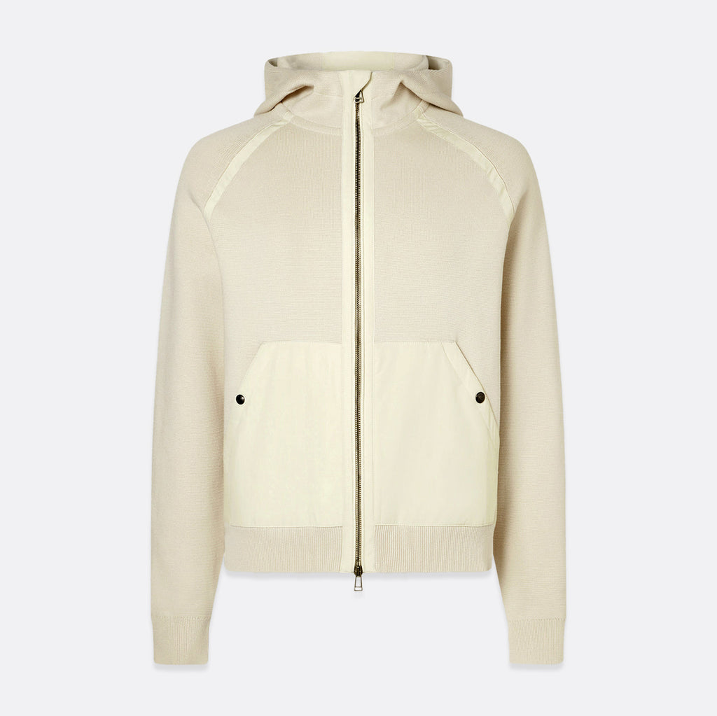 A cream-colored zip-up hoodie with a front zipper, kangaroo pockets with snap buttons, and a hood, shown against a light gray background. Belstaff Hoodie. Sakks Menswear Southampton.