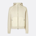A cream-colored zip-up hoodie with a front zipper, kangaroo pockets with snap buttons, and a hood, shown against a light gray background. Belstaff Hoodie. Sakks Menswear Southampton.