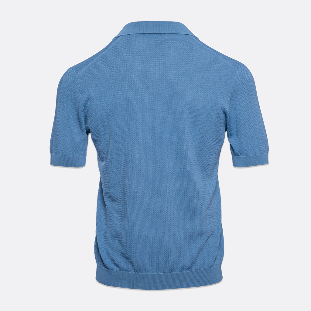 A light blue short-sleeve polo shirt shown from the back, featuring a textured knit fabric and ribbed collar, cuffs, and hem, set against a plain light grey background. Circolo 1901 Polo Shirt. Sakks Menswear Southampton.