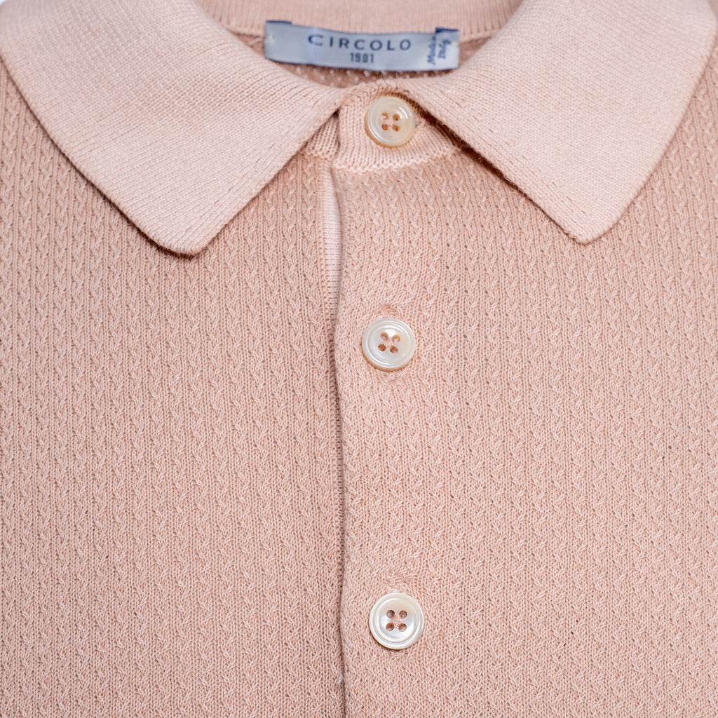 Close-up of a knit polo shirt in a soft dusty pink colour, featuring a classic collar, three cream-coloured buttons, and a visible Circolo 1911 brand label at the collar. Circolo 1901 Polo. Sakks Menswear Southampton.