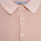 Close-up of a knit polo shirt in a soft dusty pink colour, featuring a classic collar, three cream-coloured buttons, and a visible Circolo 1911 brand label at the collar. Circolo 1901 Polo. Sakks Menswear Southampton.