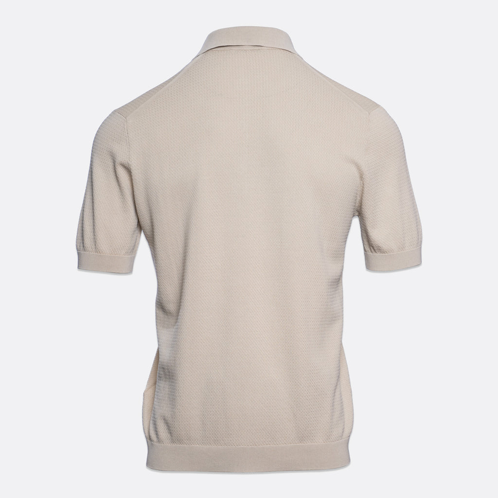 A light beige short-sleeve polo shirt shown from the back, featuring a textured knit fabric and a classic collar, set against a plain light grey background. Circolo 1901 Polo. Sakks Menswear Southampton.