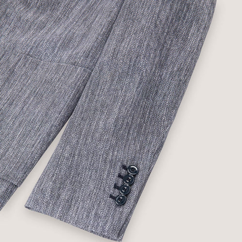 Close-up of a textured gray herringbone blazer sleeve showing three dark buttons on the cuff against a light beige background. Circolo 1901 Blazer. Sakks Menswear Southampton.