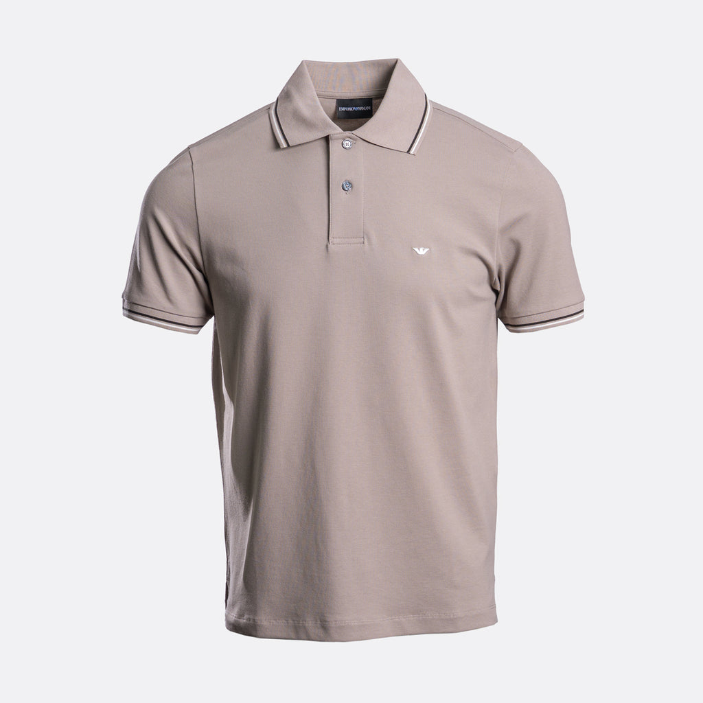 A short-sleeve polo shirt in taupe with white contrast piping on the collar and sleeve cuffs, featuring a two-button placket and a small white embroidered eagle logo on the left chest. The shirt is displayed on a clean, light grey background. Emporio Armani Polo. Sakks Menswear Southampton.