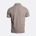 A short-sleeve polo shirt shown from the back, featuring a solid taupe-brown colour with thin white stripe accents on the collar and sleeve cuffs, set against a light grey background. Emporio Armani Polo. Sakks Menswear Southampton.