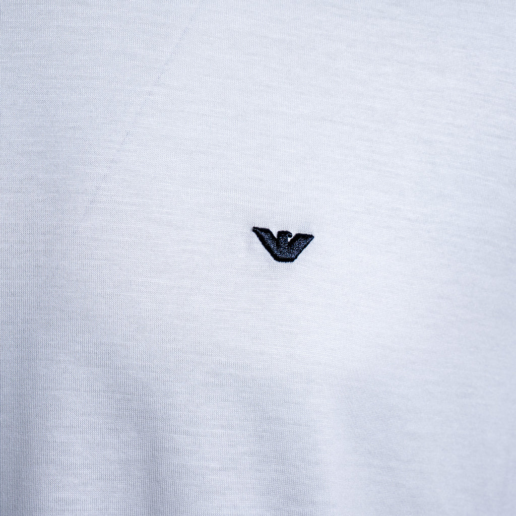 Close-up of a white heathered knit fabric with a small black embroidered Armani Privé logo centered on the chest. Emporio Armani T-Shirt. Sakks Menswear Southampton.
