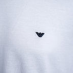 Close-up of a white heathered knit fabric with a small black embroidered Armani Privé logo centered on the chest. Emporio Armani T-Shirt. Sakks Menswear Southampton.