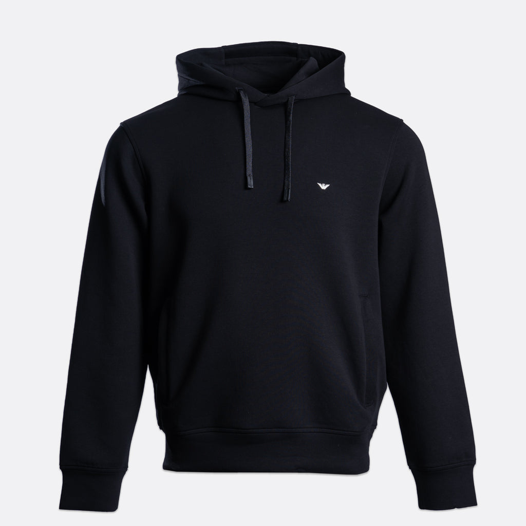 A black pullover hoodie with a small white embroidered eagle logo on the left chest, displayed on a clean light gray background. Emporio Armani Hoodie. Sakks Menswear Southampton.