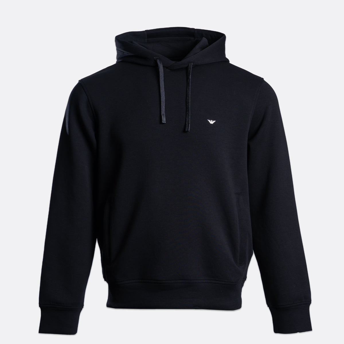 A black pullover hoodie with a small white embroidered eagle logo on the left chest, displayed on a clean light gray background. Emporio Armani Hoodie. Sakks Menswear Southampton.