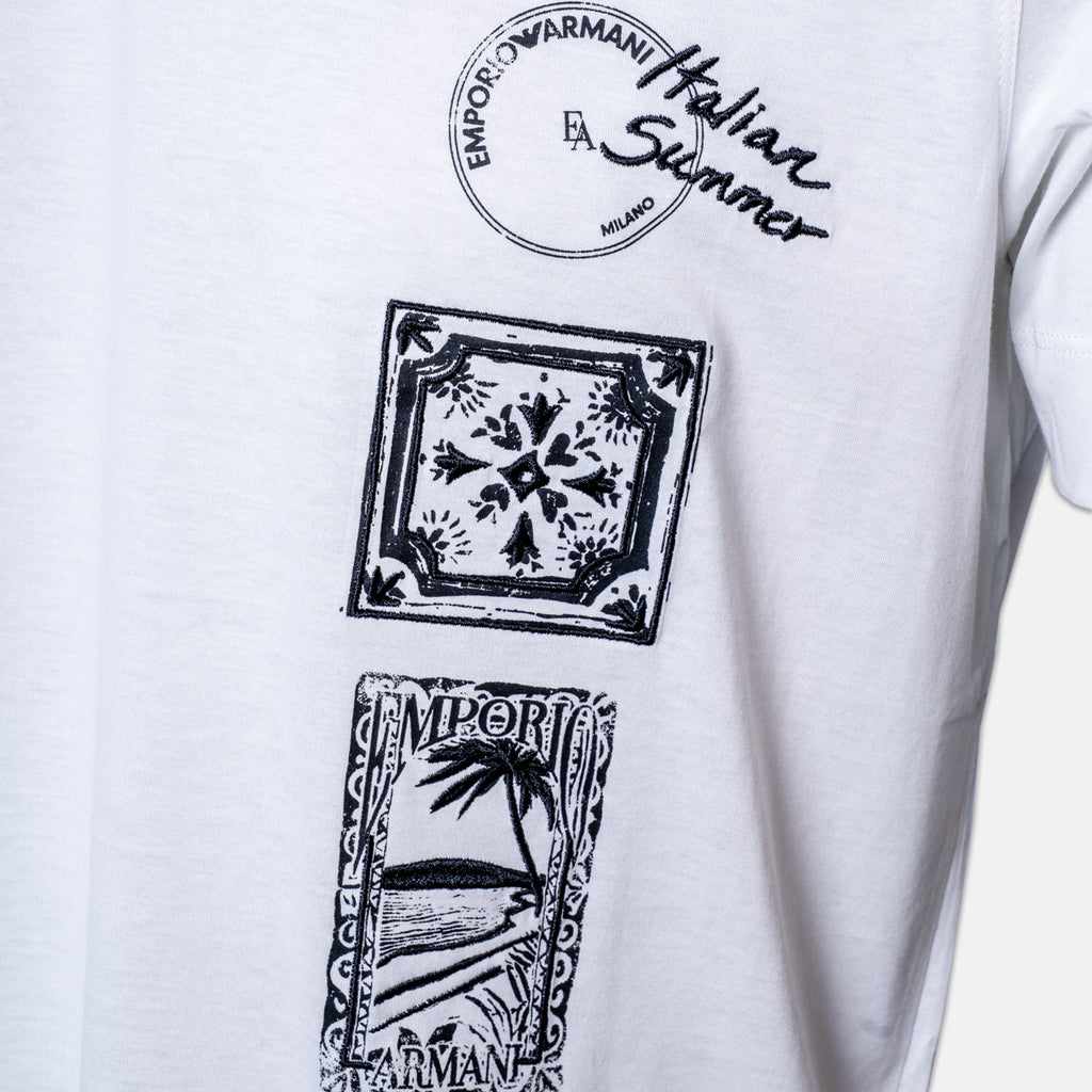 White short-sleeve T-shirt with black printed graphics: a circular 'Emporio Armani Italian Summer Milano' print at the chest, a square tile motif, and a beach scene print below. Emporio Armani T-Shirt. Sakks Menswear Southampton.