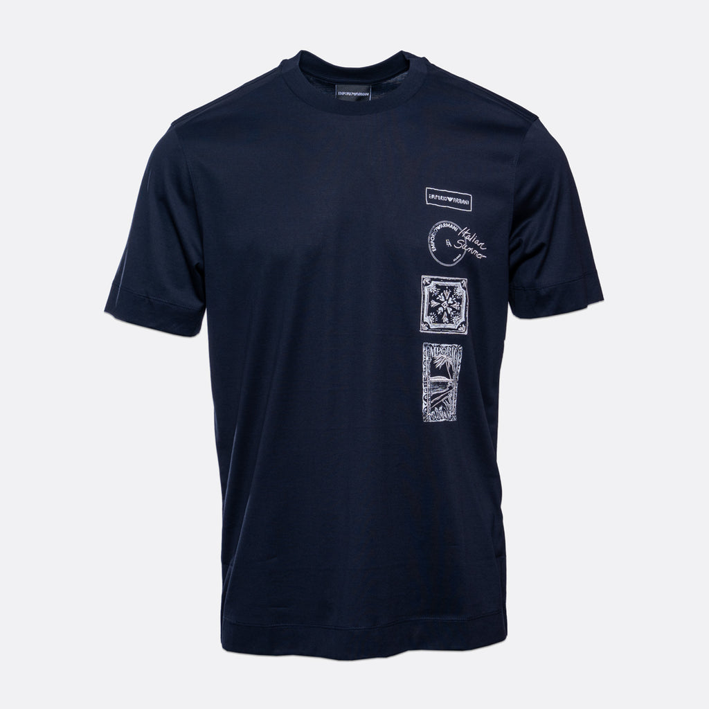 A navy blue short-sleeve t-shirt with white graphic prints on the left chest and a vertical stack of four square graphic panels on the left front. The shirt is displayed against a light gray background. Emporio Armani T-Shirt. Sakks Menswear Southampton.