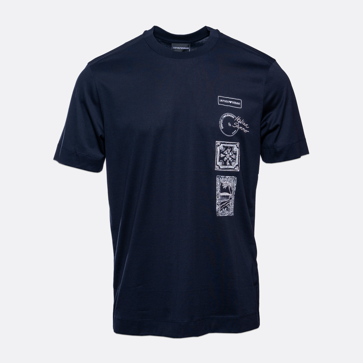 A navy blue short-sleeve t-shirt with white graphic prints on the left chest and a vertical stack of four square graphic panels on the left front. The shirt is displayed against a light gray background. Emporio Armani T-Shirt. Sakks Menswear Southampton.