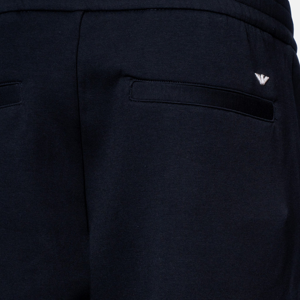 Close-up of dark navy pants showing the back pocket with a small silver embroidered logo on the upper right side. Emporio Armani Sweat Pants. Sakks Menswear Southampton.