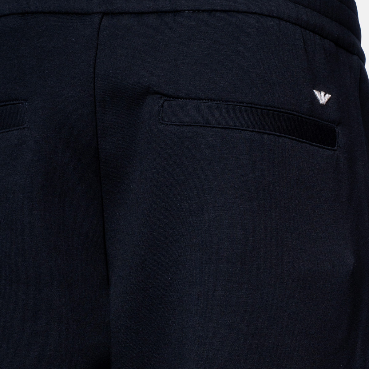 Close-up of dark navy pants showing the back pocket with a small silver embroidered logo on the upper right side. Emporio Armani Sweat Pants. Sakks Menswear Southampton.