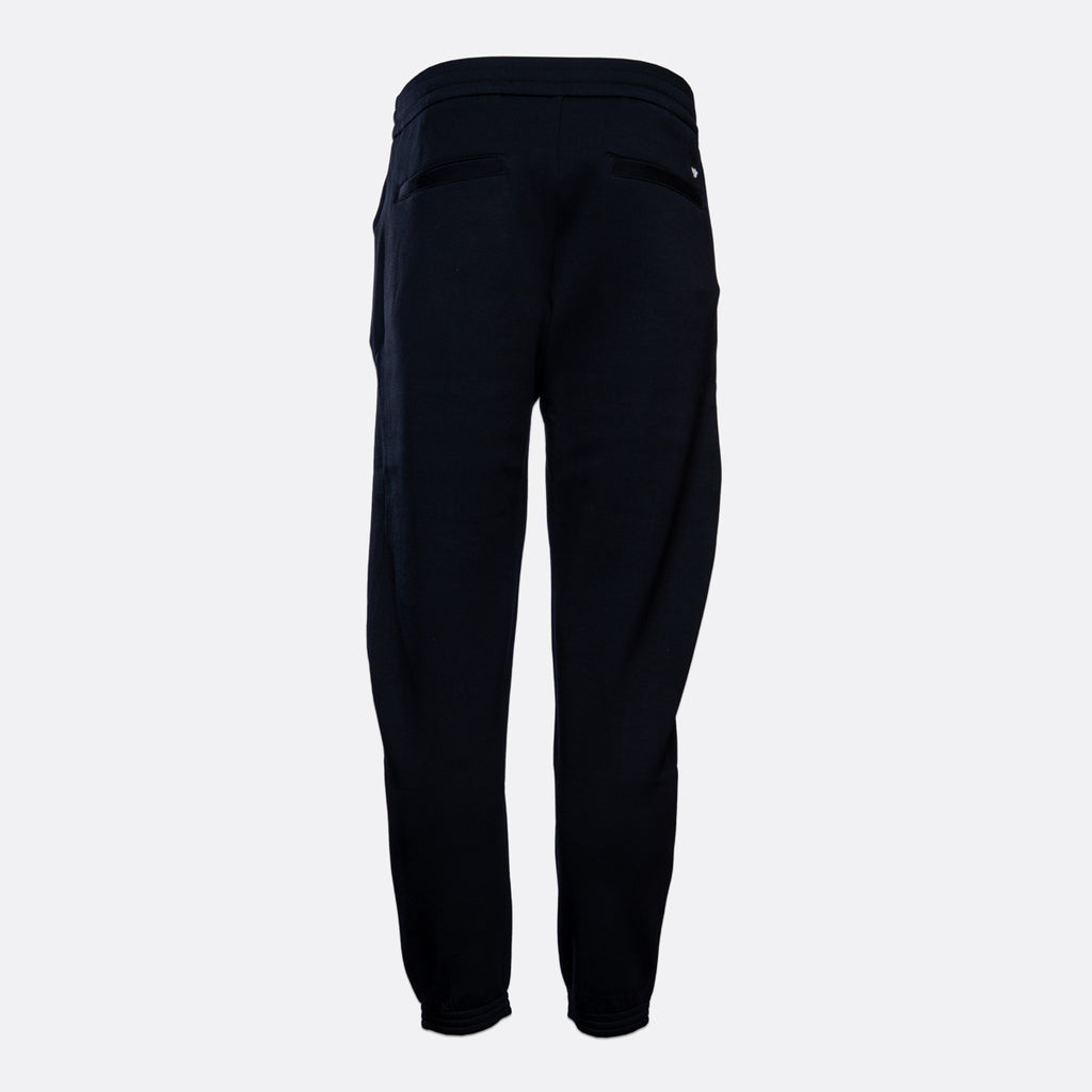 A pair of dark navy blue jogger pants shown from the back, featuring a high elastic waistband and side pockets, set against a plain light gray background. Emporio Armani Sweat Pants. Sakks Menswear Southampton.