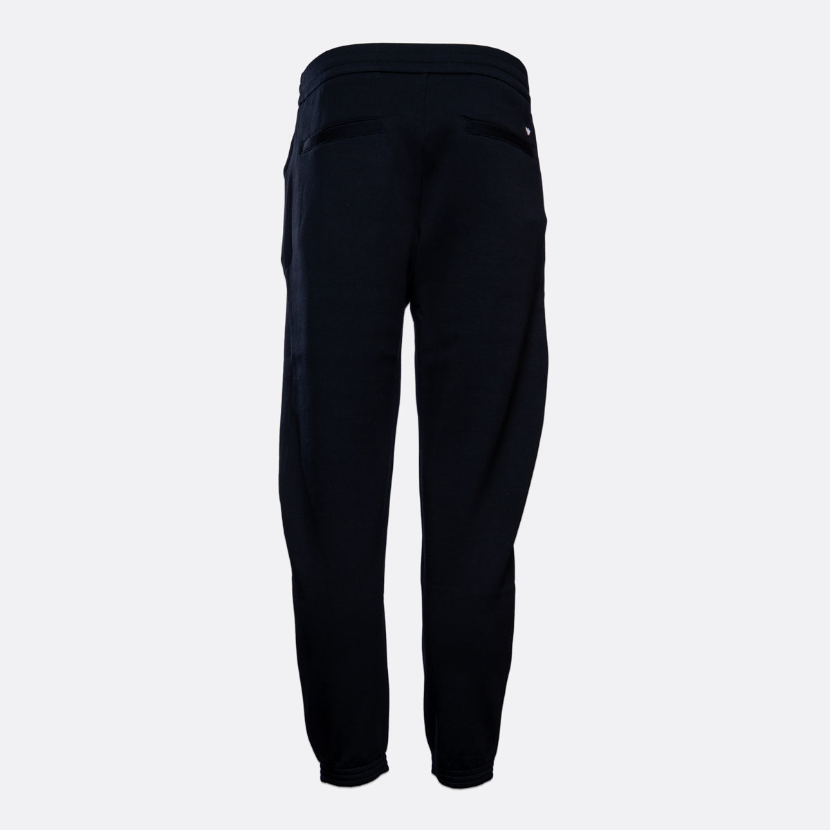 A pair of dark navy blue jogger pants shown from the back, featuring a high elastic waistband and side pockets, set against a plain light gray background. Emporio Armani Sweat Pants. Sakks Menswear Southampton.