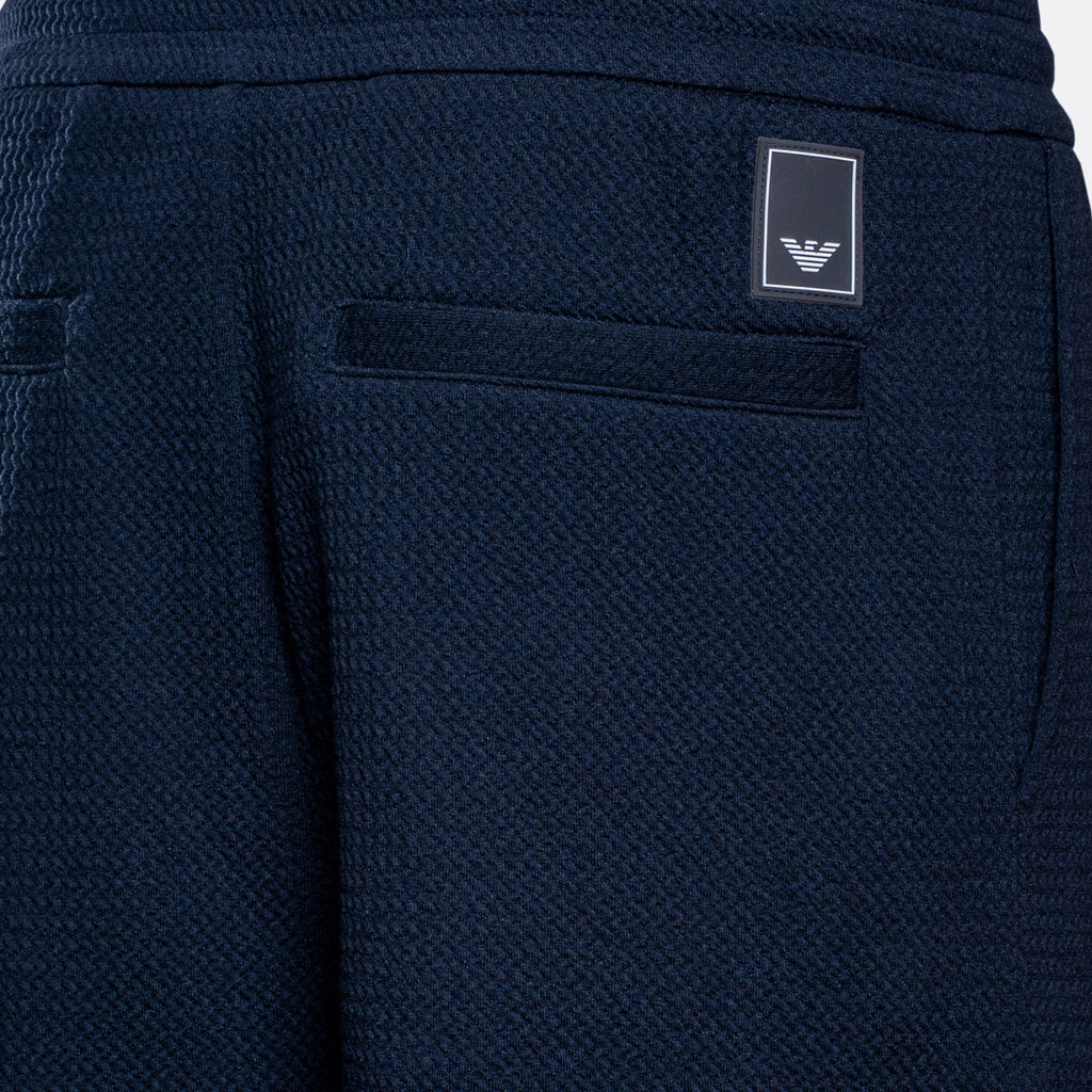 Close-up of navy blue textured fabric shorts showing a side pocket with a small rectangular Emporio Armani logo patch. Emporio Armani Sweat Pants. Sakks Menswear Southampton.