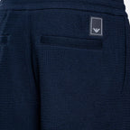Close-up of navy blue textured fabric shorts showing a side pocket with a small rectangular Emporio Armani logo patch. Emporio Armani Sweat Pants. Sakks Menswear Southampton.