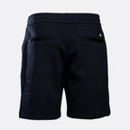 Rear view of dark navy sweat shorts with an elastic waistband, side pockets, and a small white embroidered logo on the back right pocket, shown on a light gray background. Emporio Armani Shorts. Sakk Menswear Southampton.