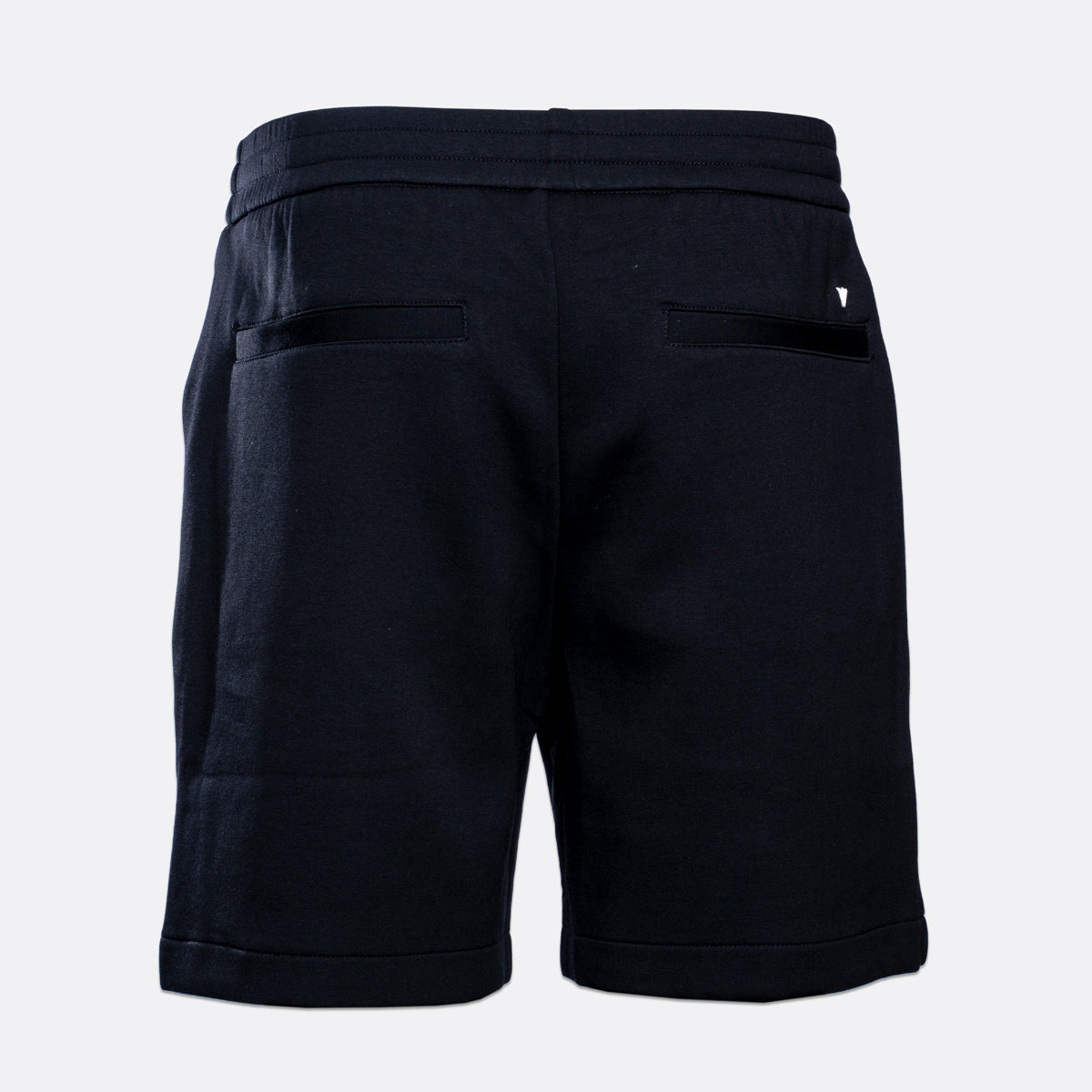 Rear view of dark navy sweat shorts with an elastic waistband, side pockets, and a small white embroidered logo on the back right pocket, shown on a light gray background. Emporio Armani Shorts. Sakk Menswear Southampton.