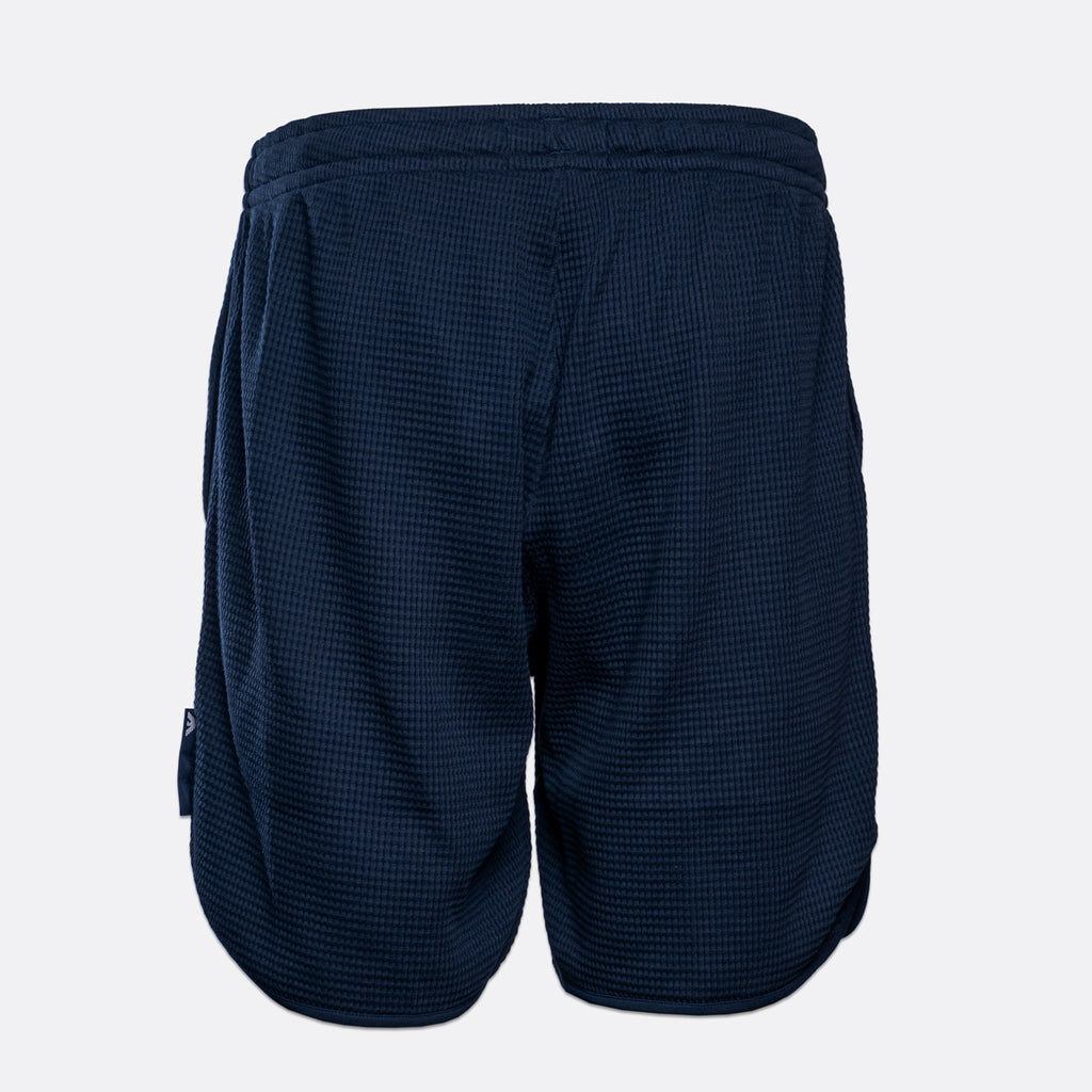 A pair of navy blue athletic shorts with a textured waffle knit fabric, shown from the back against a light gray background. Emporio Armani Shorts. Sakks Menswear Southampton.