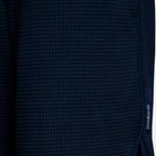 Close-up of a dark navy blue waffle-knit fabric with a small vertical woven brand tag reading EMPORIO ARMANI on the right side. Emporio Armani Shorts. Sakks Menswear Southampton.