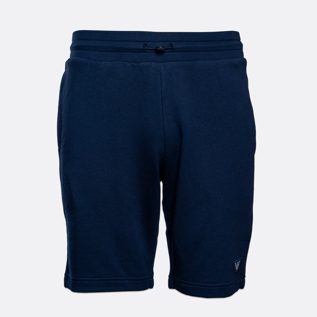 A pair of navy blue sweat shorts with an elastic waistband and drawstring, shown against a light gray background. Emporio Armani Shorts. Sakks Menswear Southampton.