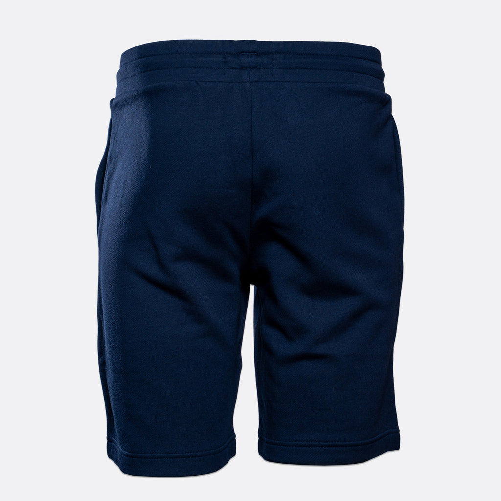 A pair of navy blue sweat shorts shown from the back, featuring an elastic waistband and side pockets, set against a plain light gray background. Emporio Armani Shorts. Sakks Menswear Southampton.