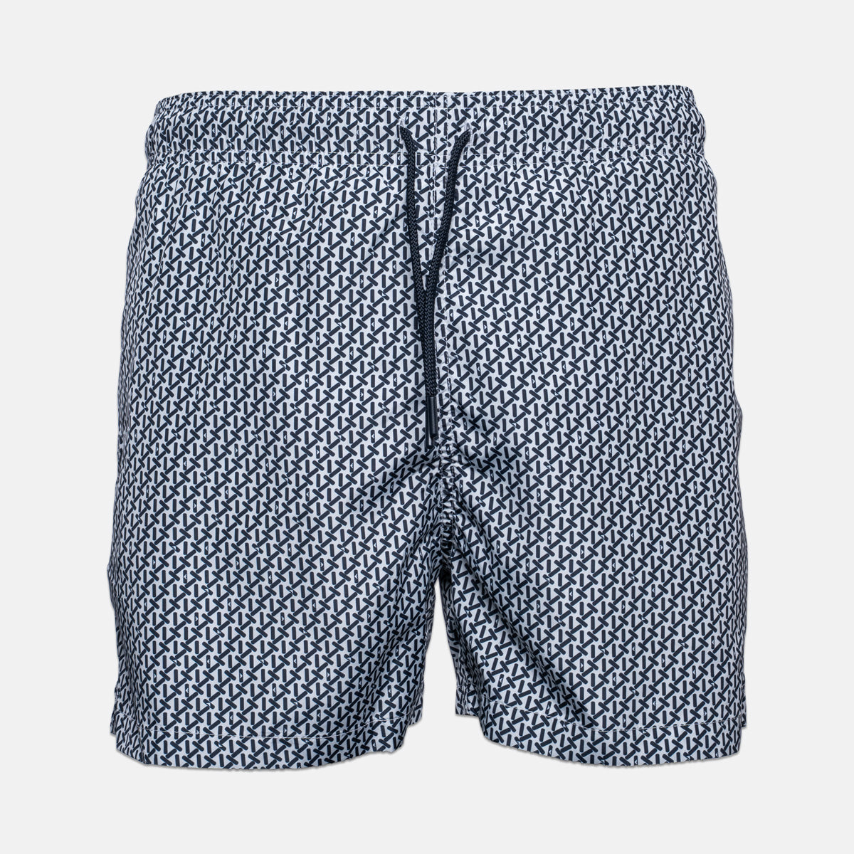 A pair of men's swim trunks featuring an all-over repeating geometric pattern in navy blue and white, with a matching navy drawstring at the elastic waistband, shown against a light gray background. Emporio Armani Swim shorts. Sakks Menswear Southampton.