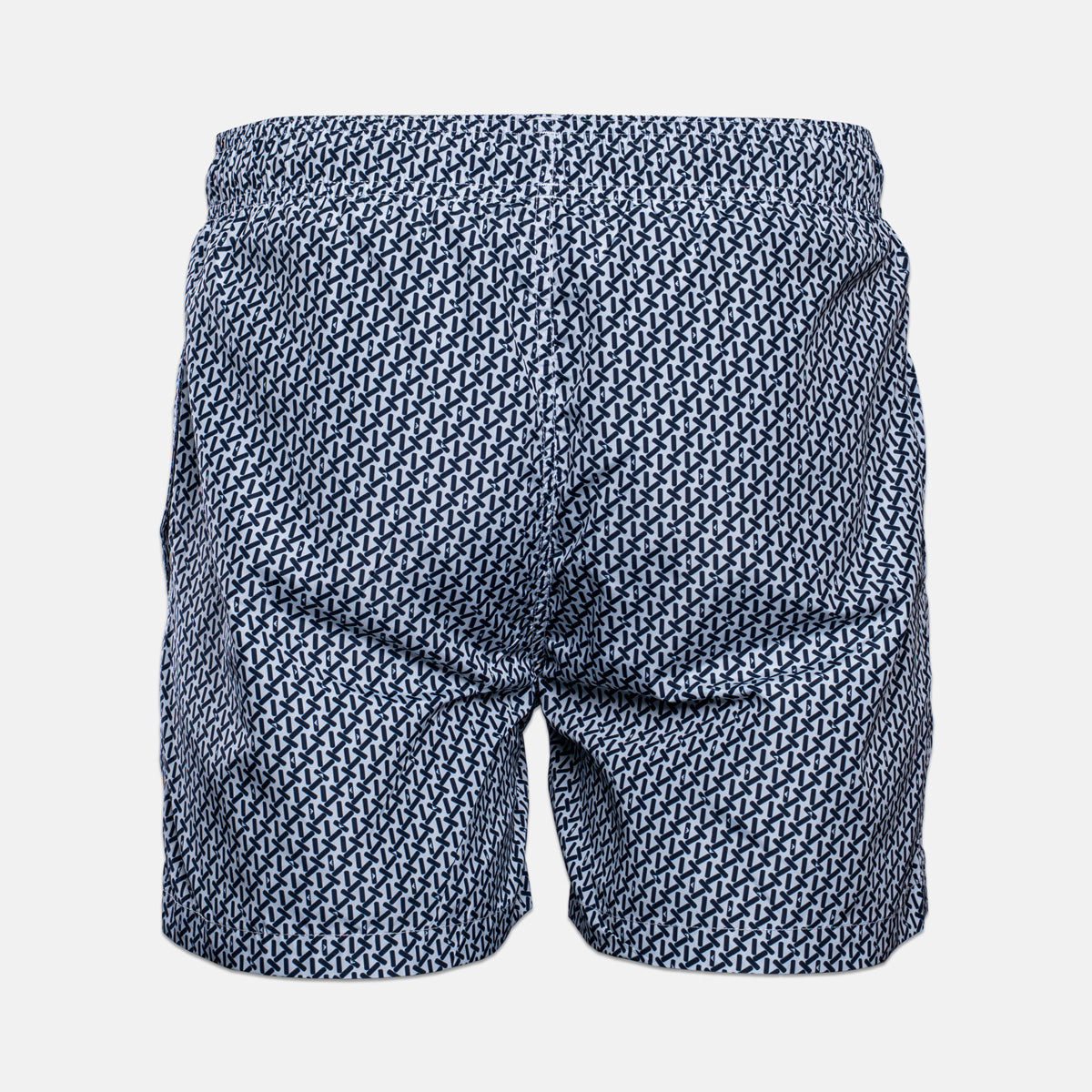A pair of men's swim trunks featuring a dense, repeating geometric pattern in navy blue and white, shown from the back against a light gray background. Emporio Armani Swim shorts. Sakks Menswear Southampton.
