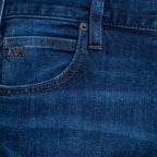 Close-up of dark blue denim jeans showing the back pocket with contrast stitching and a small metal logo patch. Emporio Armani Jeans. Sakks Menswear Southampton.