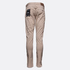 A pair of slim-fit beige trousers shown from the back, featuring a brown leather waistband patch and a black brand label on the right pocket, set against a plain light gray background. Emporio Armani Chinos. Sakks Menswear Southampton.