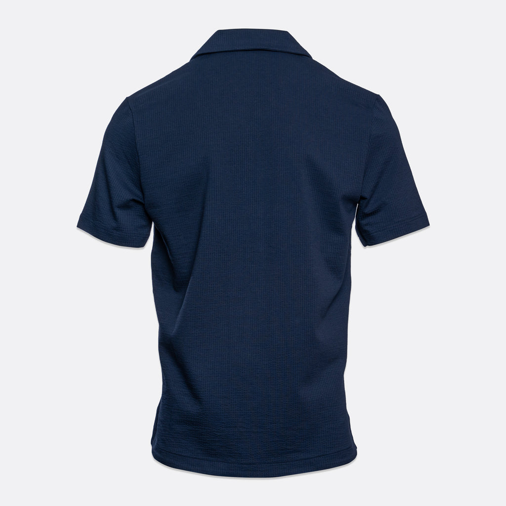 A dark navy blue short-sleeve polo shirt shown from the back, displayed on a clean, light gray background. Emporio Armani Short Sleeve Shirt. Sakks Menswear Southampton.