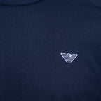 Close-up of a navy blue crewneck sweatshirt featuring the white embroidered logo of Emporio Armani on the chest. Emporio Armani T-Shirt. Sakks Menswear Southampton.