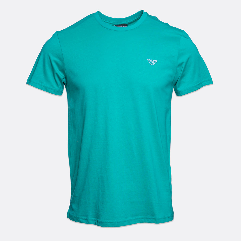A teal short-sleeve crewneck t-shirt with a small white embroidered logo on the left chest, displayed on a light gray background. Emporio Armani T-Shirt. Sakks Menswear Southampton.