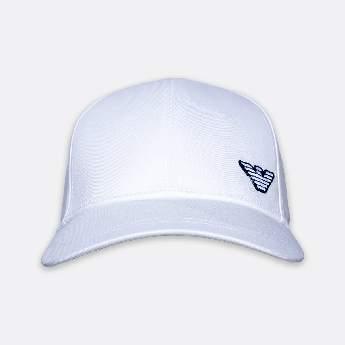 A white structured baseball cap with a curved brim and a small dark embroidered logo on the side, shown against a light gray background. Emporio Armani Cap. Sakks Menswear Southampton.