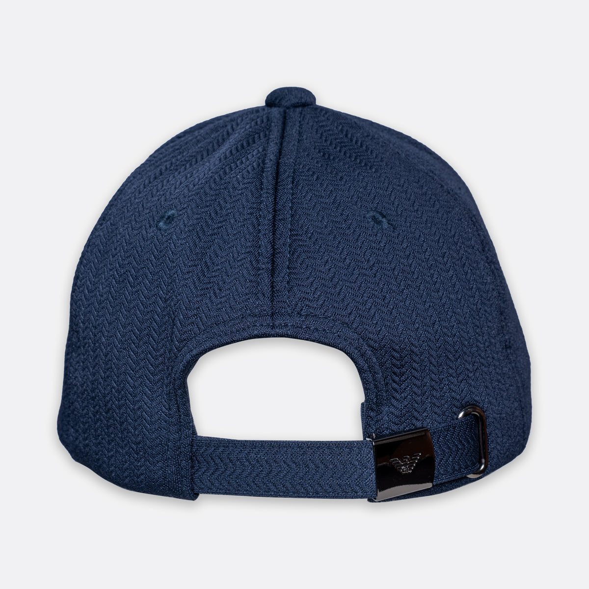 The back view of a navy blue baseball cap with a textured herringbone pattern and an adjustable strap with a black plastic toggle. Emporio Armani Cap. Sakks Menswear Southampton