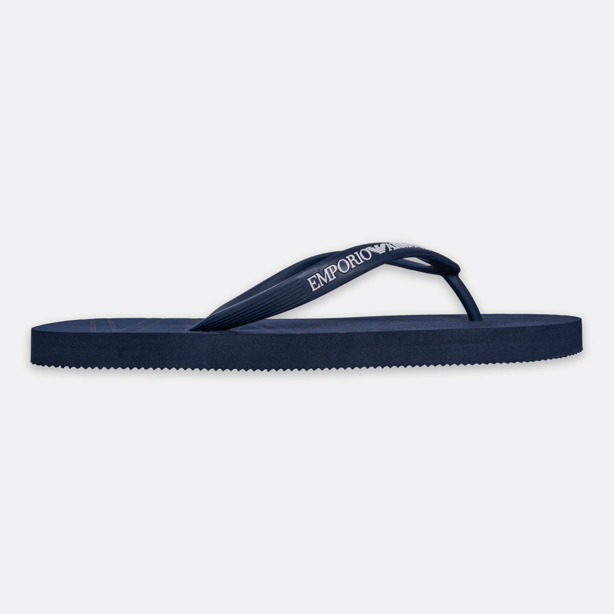 A single navy blue flip-flop sandal with the brand name 'EMPORIO ARMANI' printed in white on the strap, shown against a light gray background. Emporio Armani Flip Flops. Sakks Menswear Southampton.